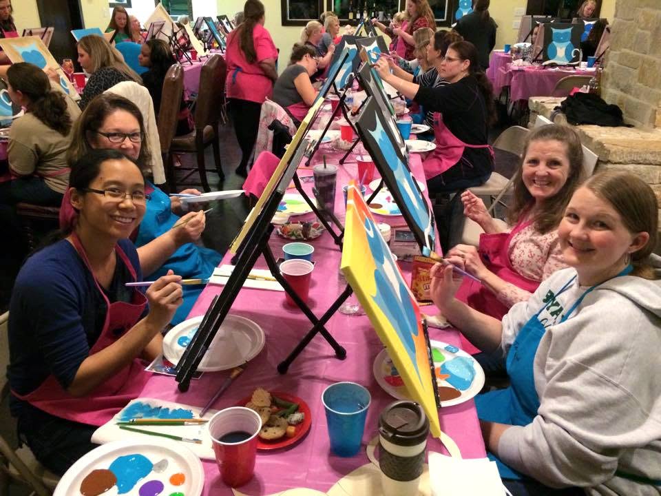 Guests enjoying a group paint party around easels